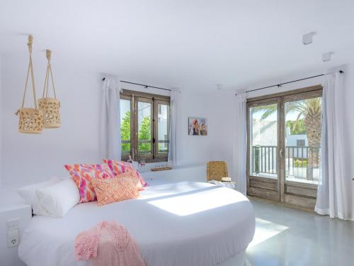 a white bedroom with a large bed and a balcony at Villas S'Argamassa in Santa Eularia des Riu