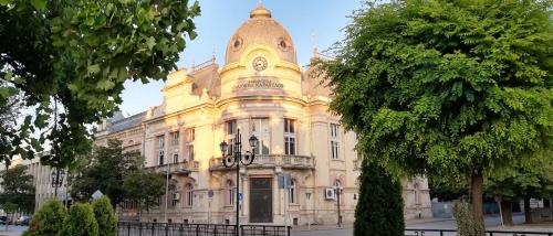 a large yellow building with a clock on it at Sky Blue Danube Apartment Ruse in Ruse