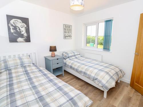 a bedroom with two beds and a window at 6 Yarmouth Cottages in Freshwater