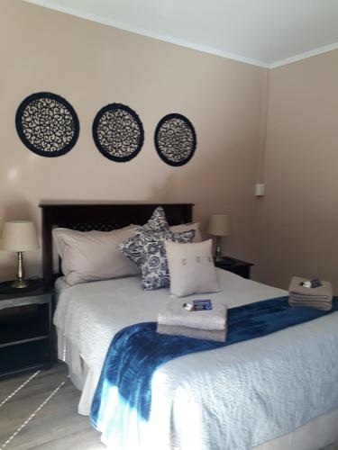a bedroom with a bed with pillows and clocks on the wall at KIHARA GUESTHOUSE in Bethlehem