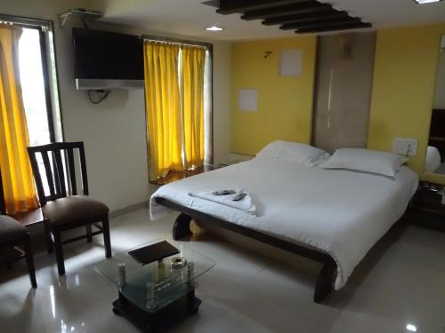 a bedroom with a bed and a chair and a table at Hotel Arma Court - Near US Embassy, BKC in Mumbai
