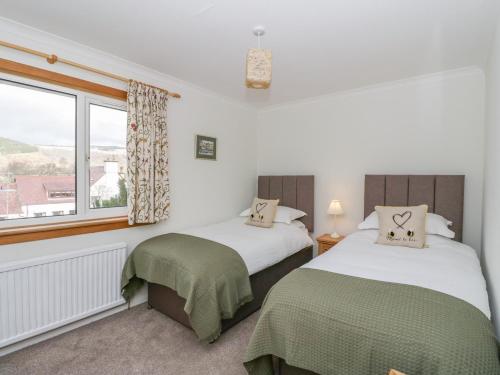 two beds in a room with a window at Cromallt in Aberfeldy