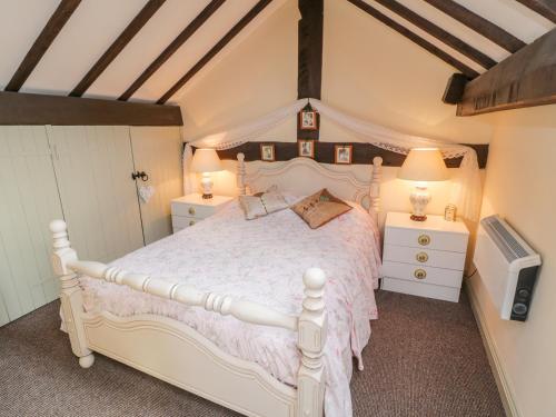 een slaapkamer met een wit bed en een televisie bij Old Stables Cottage in Saltburn-by-the-Sea
