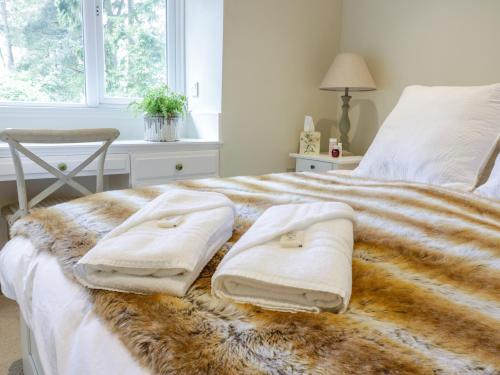 een slaapkamer met een bed met twee handdoeken erop bij Gate Lodge in West Calder