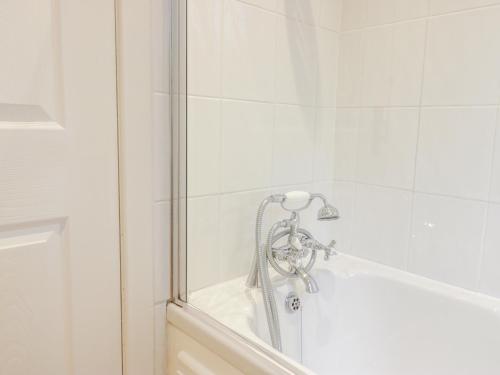 a bath tub with a shower head in a bathroom at Gate Lodge in West Calder