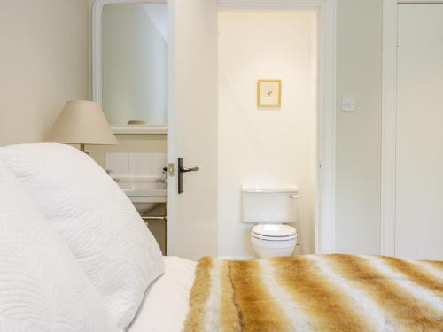 een witte slaapkamer met een bed en een toilet bij Gate Lodge in West Calder