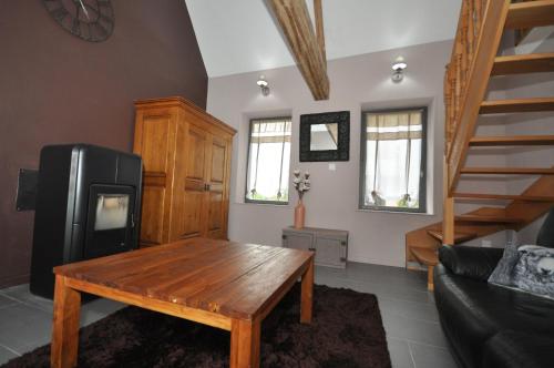 a living room with a wooden table and a couch at Gîte de La Broderie in Bersée