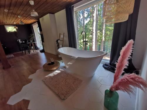 a bathroom with a large window and a white bath tub at Lodge "Ezīša Midziņa" in Ķegums