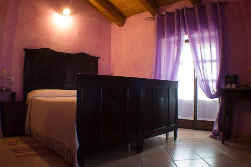 a bedroom with a bed and a window with purple curtains at Agriturismo La Cà Veja in Monforte dʼAlba