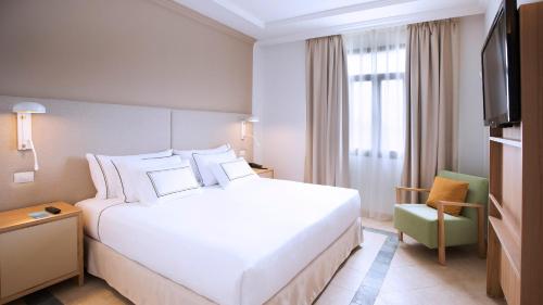 a hotel room with a white bed and a chair at Melia Villaitana in Benidorm