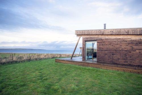 a small brick house with a window on a grass field at John O'Groats in John O Groats