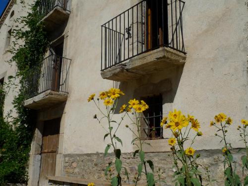 a building with a balcony and yellow flowers at Cal Calsot Casa Rural "Adults Only" in Montellá