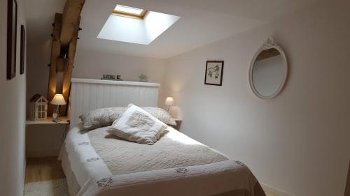 ein weißes Schlafzimmer mit einem Bett und einem Spiegel in der Unterkunft La Ferme des Andes - Gîte l'Atelier in Quins