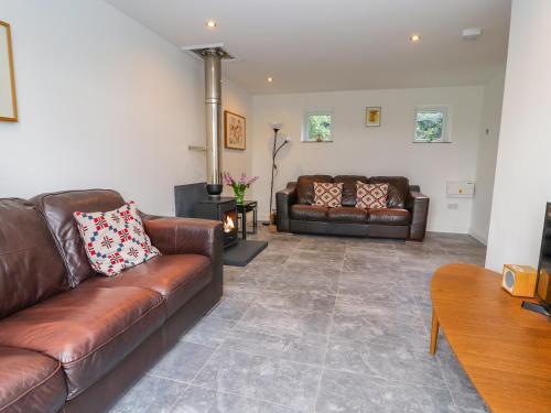 a living room with two leather couches and a fireplace at The Stables in Frodsham