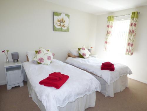 two beds in a room with red towels on them at The Bungalow in Burnley