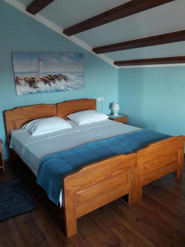 a bedroom with a wooden bed with a light blue wall at Car free island Unije Gasparini apartments in Unije