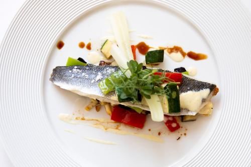 a white plate with a piece of fish and vegetables at Art Hotel Kaštieľ in Tomášov