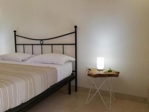 1 dormitorio con 1 cama y 1 mesa con lámpara en Le stanze di Ray, en Borgagne