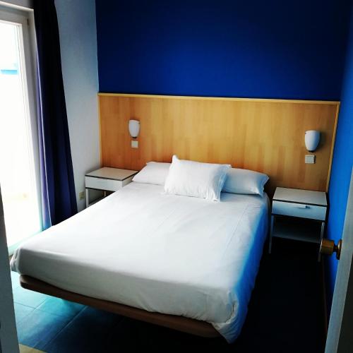 a bedroom with a large white bed with blue walls at Hotel Eira Da Pedra in Vila Nova de Milfontes