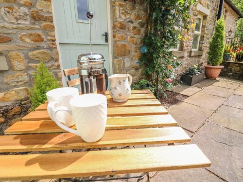 a wooden table with two cups on top of it at Spens Farm Cottage in Lancaster