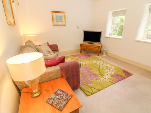 a living room with a couch and a television at Spens Farm Cottage in Lancaster
