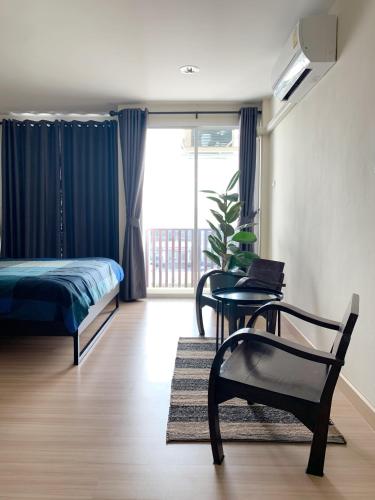 a bedroom with a bed and a chair and a table at Hostbox Bangkok in Lat Krabang