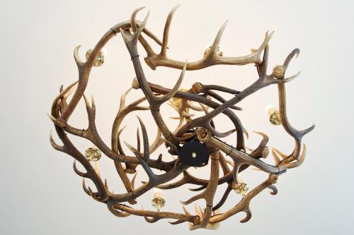 a brass chandelier with antlers and a black button at John O'Groats in John O Groats