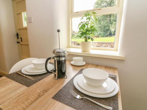 einen Tisch mit Platten und Schüsseln auf einem Tisch mit einem Fenster in der Unterkunft Spens Farm Cottage in Lancaster