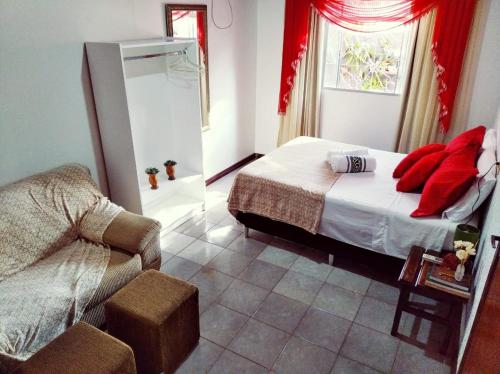 a bedroom with a bed with red pillows and a chair at Gardenia House in Foz do Iguaçu
