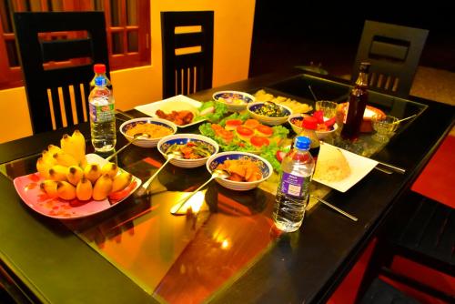 a table topped with bowls of food and bottles of water at Ceylon Safari Cottage in Udawalawe