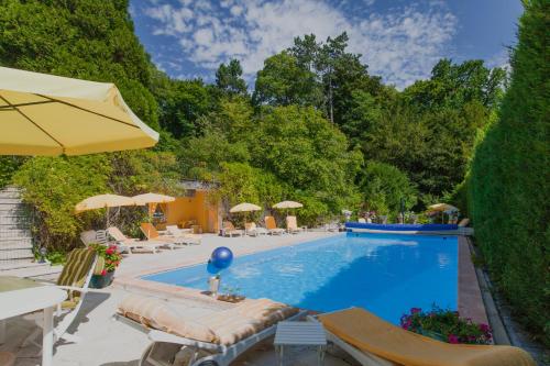 a swimming pool with chairs and umbrellas in a yard at Manoir des Cavaliers - BnB in Chantilly