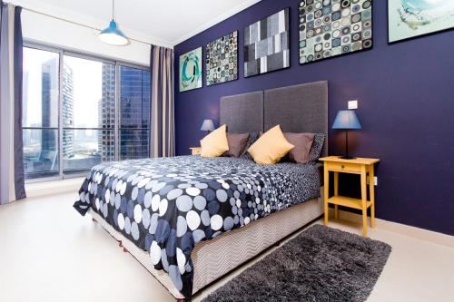 a bedroom with a large bed and a purple wall at Quintessential Quarters - Ultra-modern and Spacious Aparment in Dubai