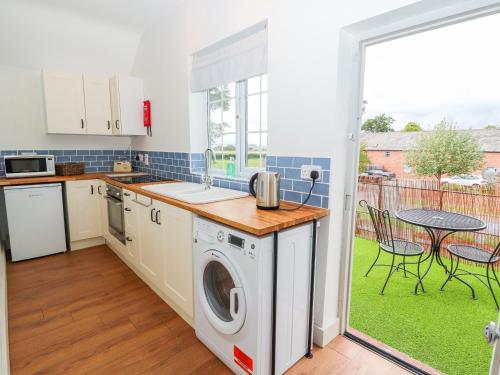 a kitchen with a washing machine and a table with chairs at Well House Farm Flat 2 in Chester