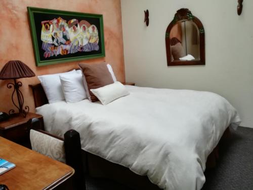 a bedroom with a large white bed and a table at Hotel Ciudad Vieja in Guatemala