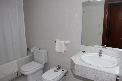 a bathroom with a sink and a toilet and a mirror at Apartamentos Marina in Port de Pollensa
