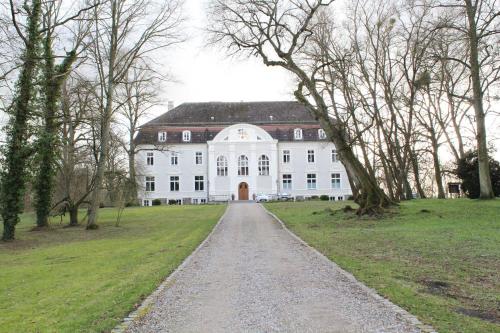 a large white house with a gravel road in front at Schloss Zinzow in Zinzow