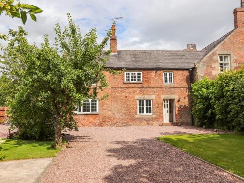 an old brick house with a tree in front of it at Well House Farm Flat 2 in Chester