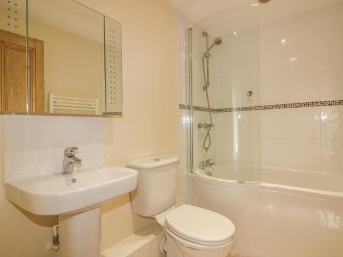 Un baño con inodoro, lavabo y ducha. en Polstein, en Truro