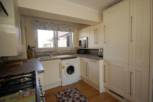 a kitchen with a washing machine and a window at Broxbourne Two-Bedroom Apartment Close To Amenities in Hoddesdon