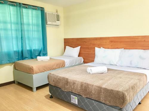 2 Betten in einem Hotelzimmer mit blauen Vorhängen in der Unterkunft Johann’s Place Panglao in Panglao