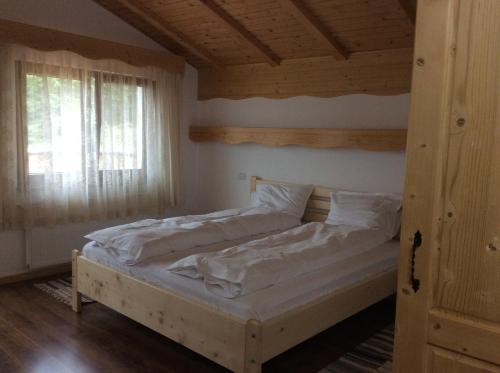 a bedroom with a bed with white sheets and a window at Pensiunea L`Amoro in Neagra Şarului