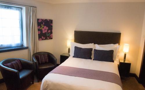 Habitación de hotel con cama y silla en Aaron Glen Guest House, en Loanhead