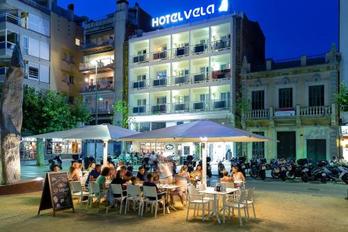 a group of people sitting at tables in front of a building at Hotel Vela in Roses