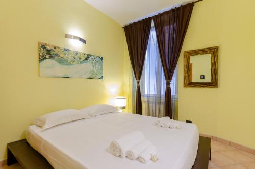 Un dormitorio con una cama blanca con toallas. en JOIVY Warm Family Apt near Porto Antico, en Génova