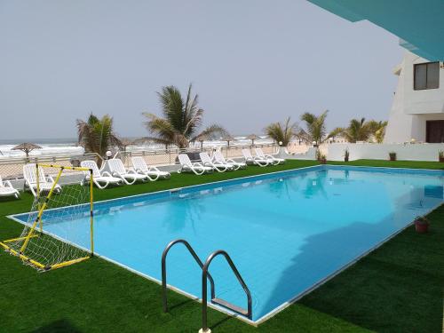 a large swimming pool with chairs and a swing at Salalah Beach Villas in Salalah