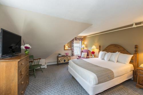 a hotel room with a large bed and a flat screen tv at Eagle Mountain House and Golf Club in Jackson