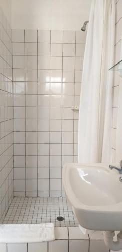 La salle de bains blanche est pourvue d'un lavabo et d'une douche. dans l'établissement Forestview guesthouse and B&B, à Sedgefield