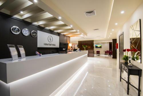 una hall con bancone della reception e orologi appesi al muro di Hôtel Sidi Yahia a Alger