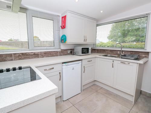 a white kitchen with white cabinets and windows at 201 Norton Park in Dartmouth