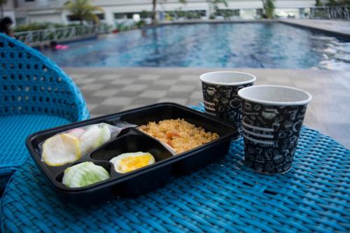 a tray of food on a table next to two cups at Titanium Express HomTel in Jakarta